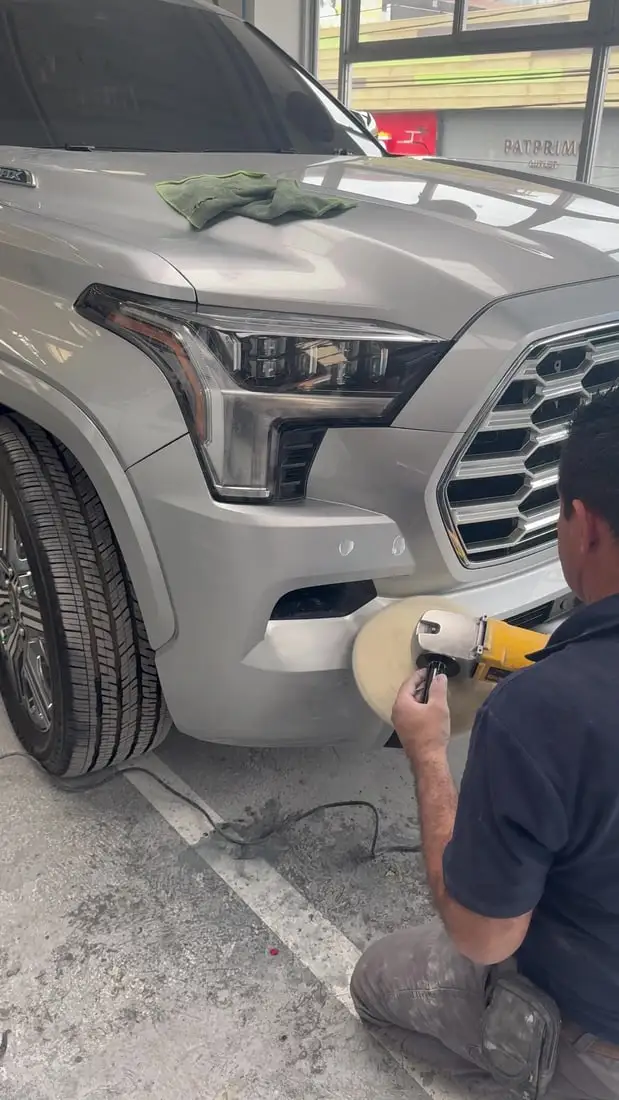 Técnico puliendo el bómper de una camioneta Toyota con pulidora rotativa